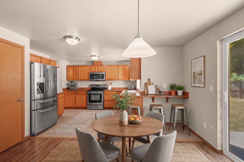 Virtually staged kitchen and dining area with round table and warm wood cabinetry