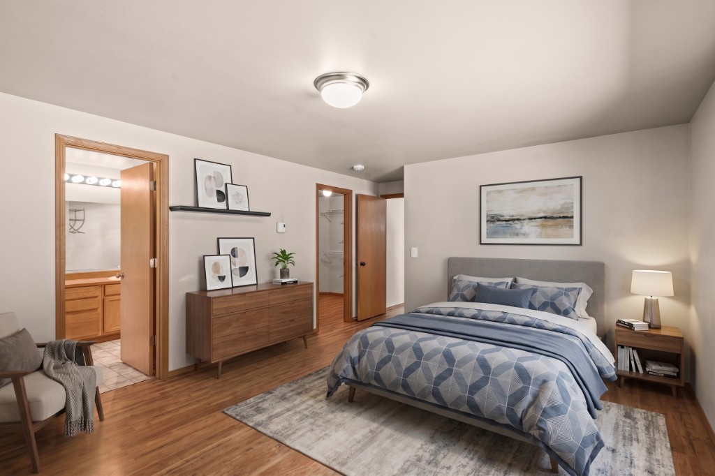Virtually staged master bedroom with neutral bedding and hardwood floors