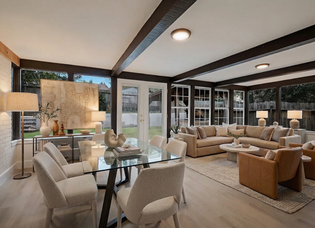 Virtually staged open-concept living and dining room with exposed wood beams